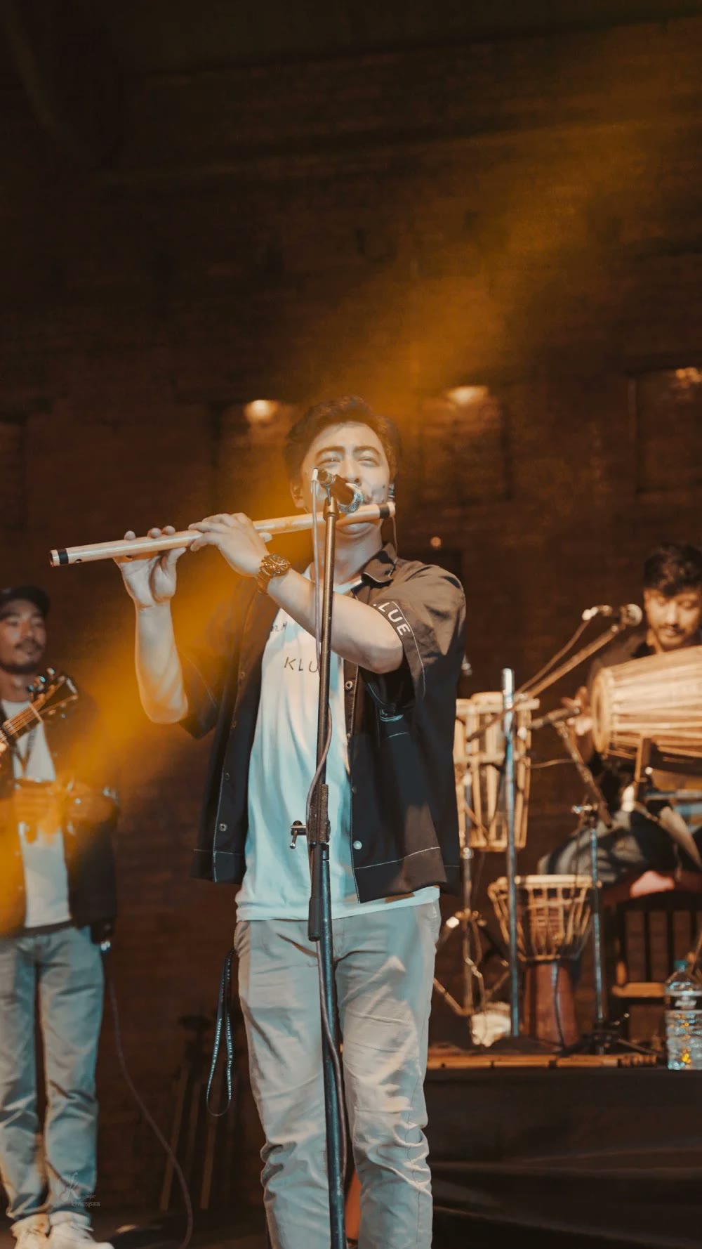 A Khwopa Band member playing bansuri under stage lights