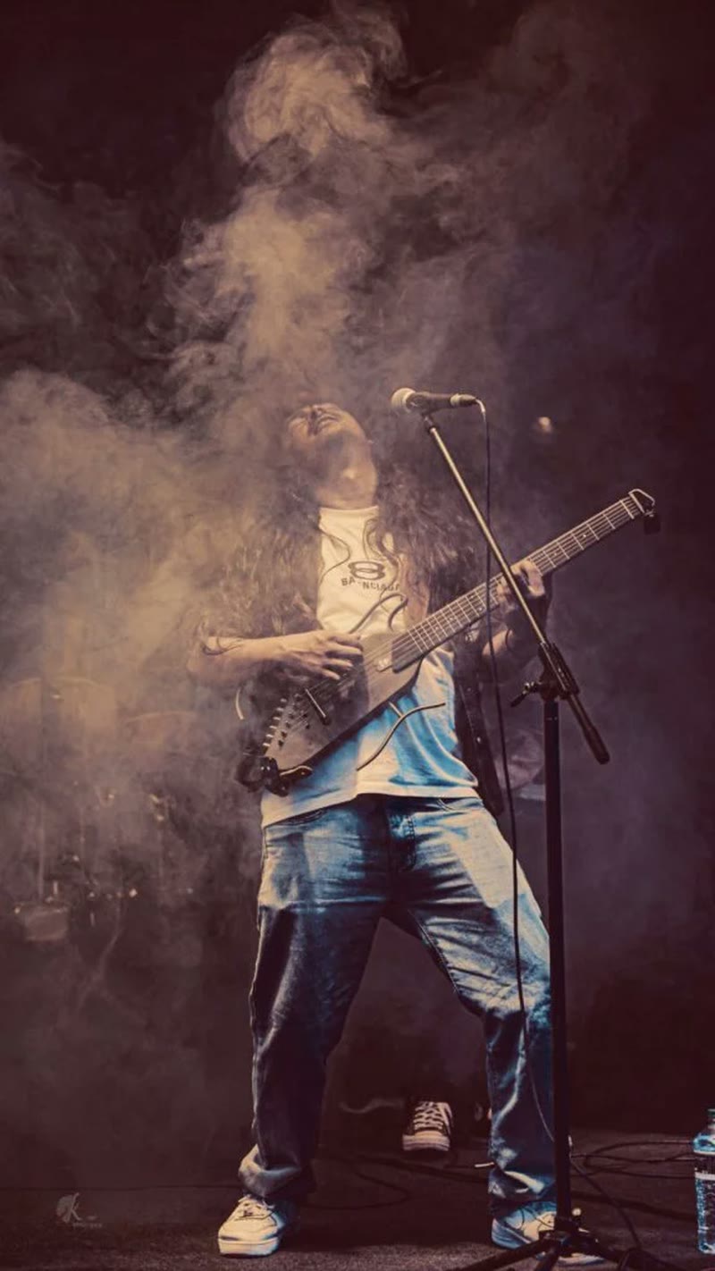 A sarangi player silhouetted in stage haze